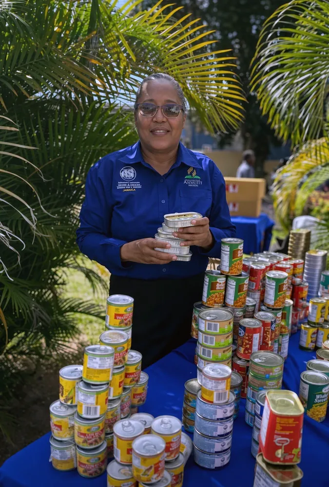 Loretta Daley, Church Coordinator, with tinned food collected for relief